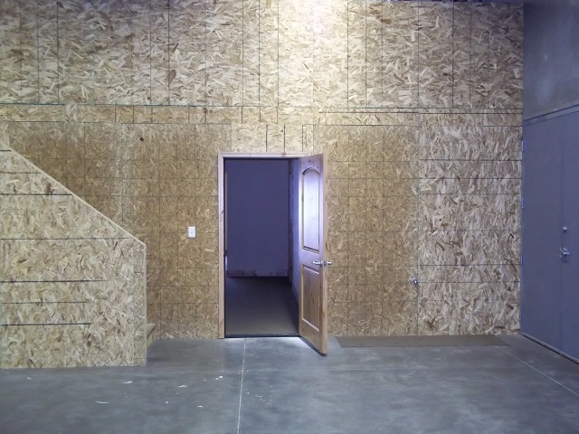 Unfinished flex bay interior with OSB walls, mezzanine, and interior door